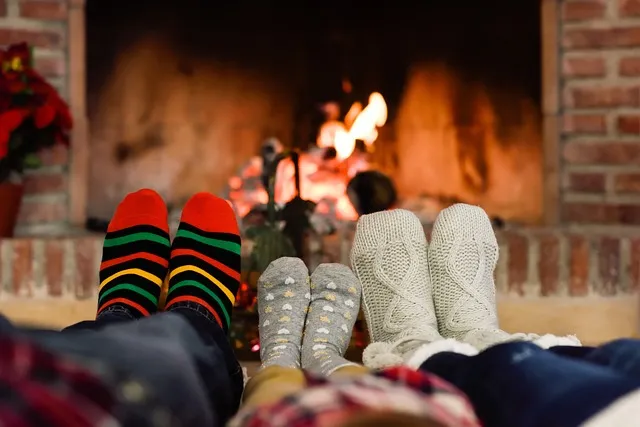 A view of a family's feet warming by fireplace
