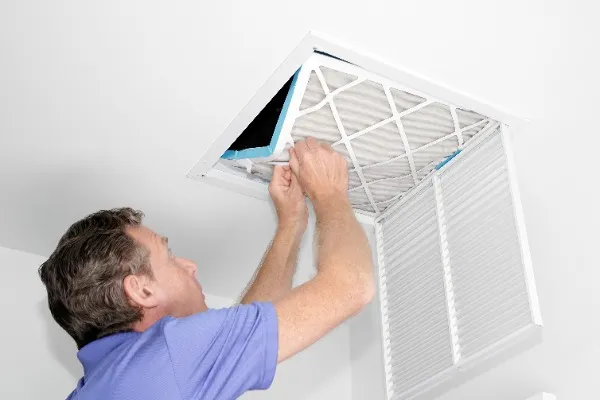 A dirty AC filter being removed by a tech.