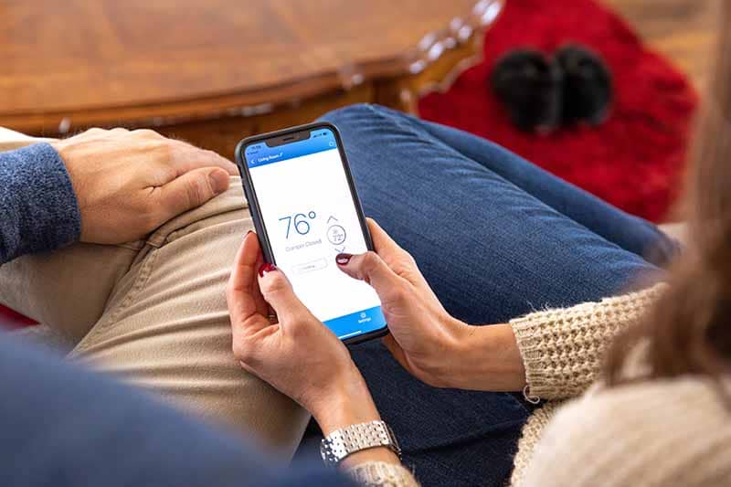 A couple looking at their house's temperature on their phone.