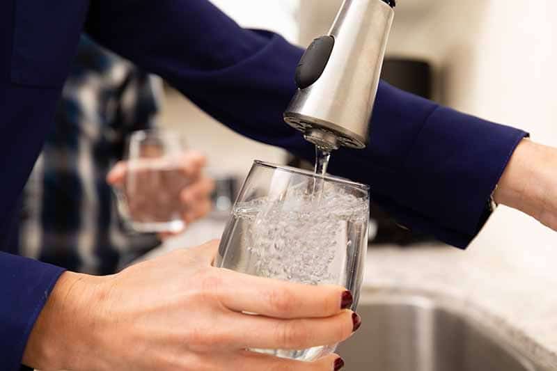 A customer filling a glass full of water.