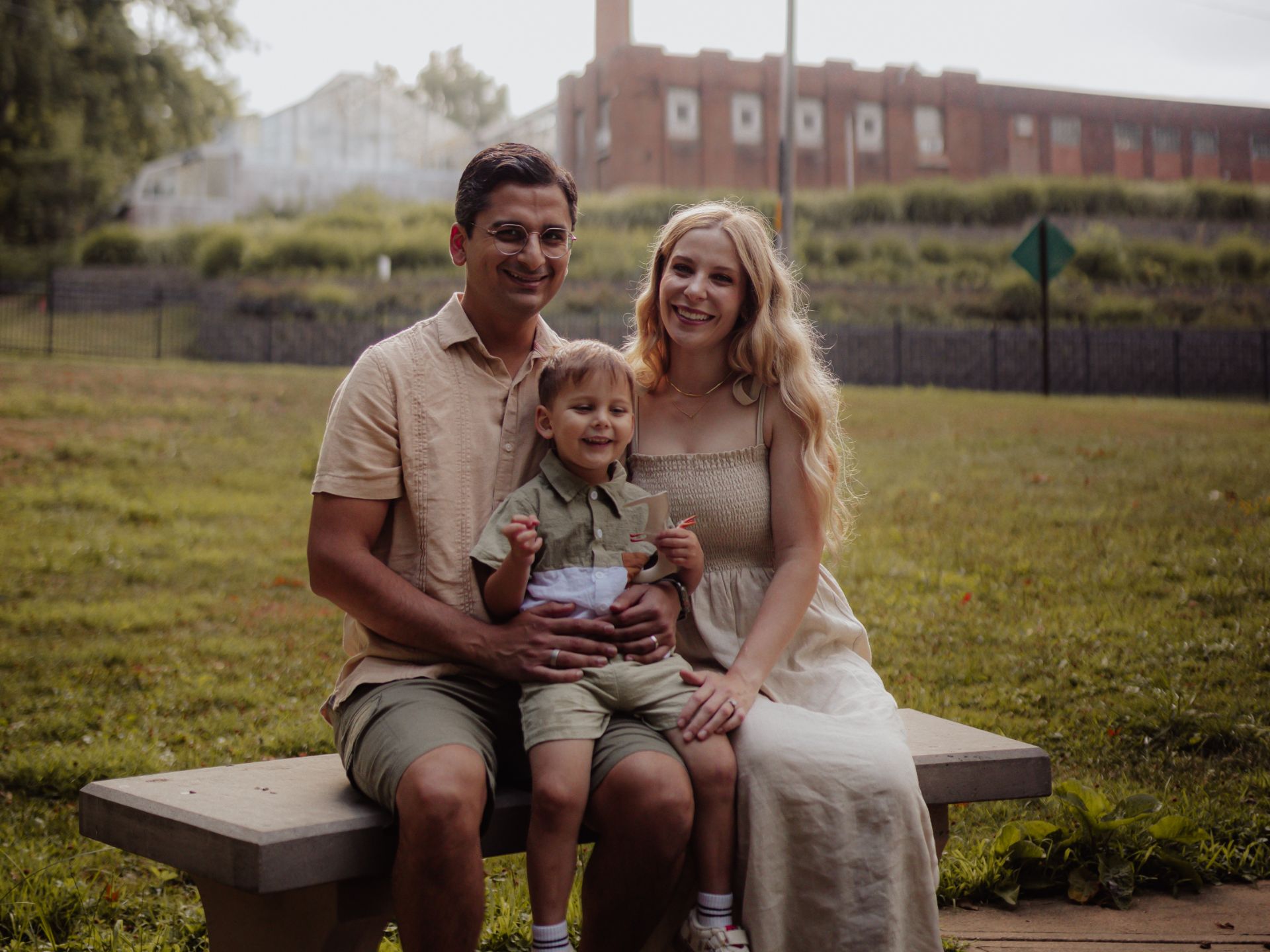 Smiling family of three sitting on a park bench in Westfield Center, OH