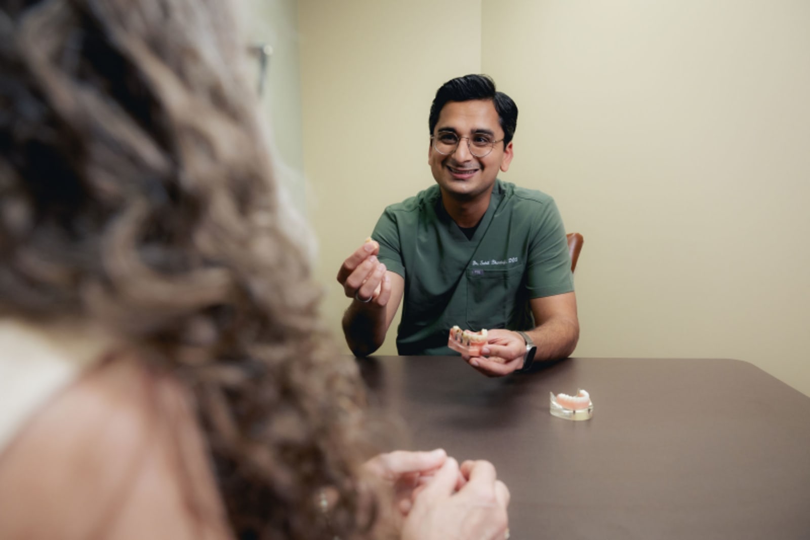 Male dentist demonstrating treatment procedure with patient at consultation table