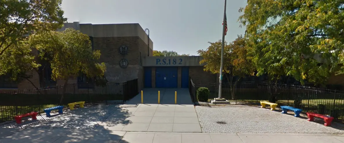 Exterior front entrance of P.S. 182 school building with flagpole