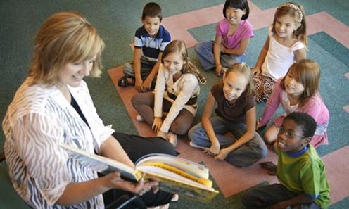 Teacher reading a book aloud to a group of young students
