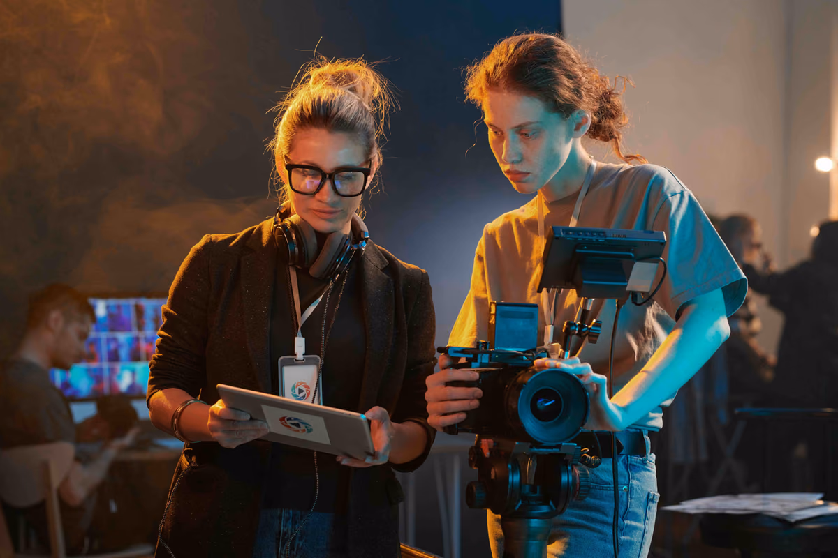 Two directors reviewing a shot on a tablet beside a camera on a dimly lit set