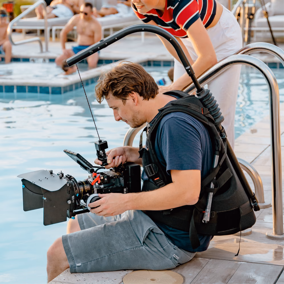 Director of photography adjusting a cinema camera at the edge of a swimming pool