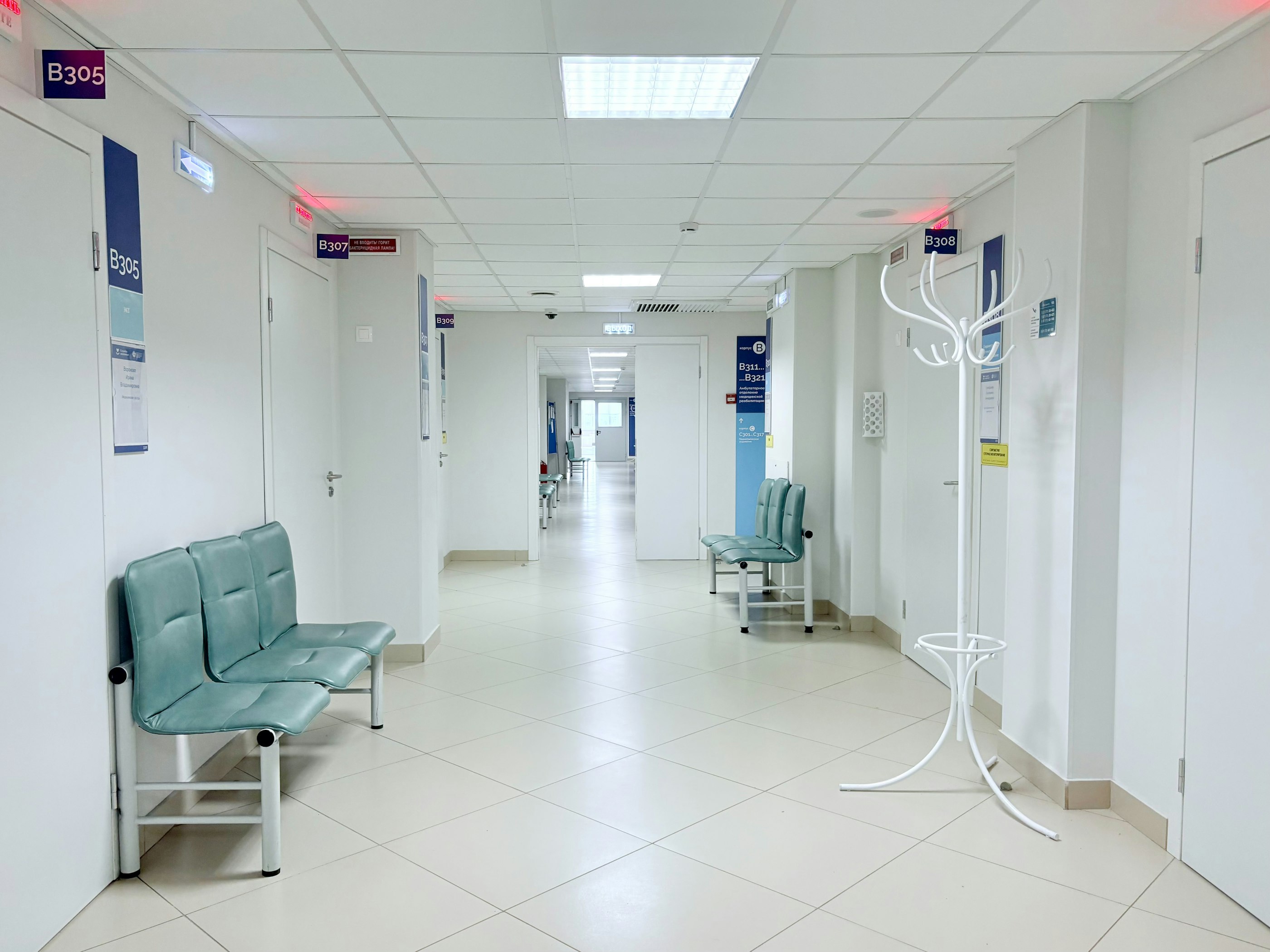 Empty hospital corridor lined with doors and benches