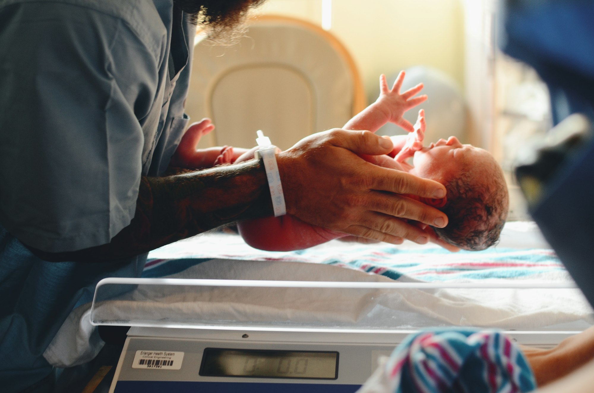 A newborn being weighed by a clinician in a hospital nursery