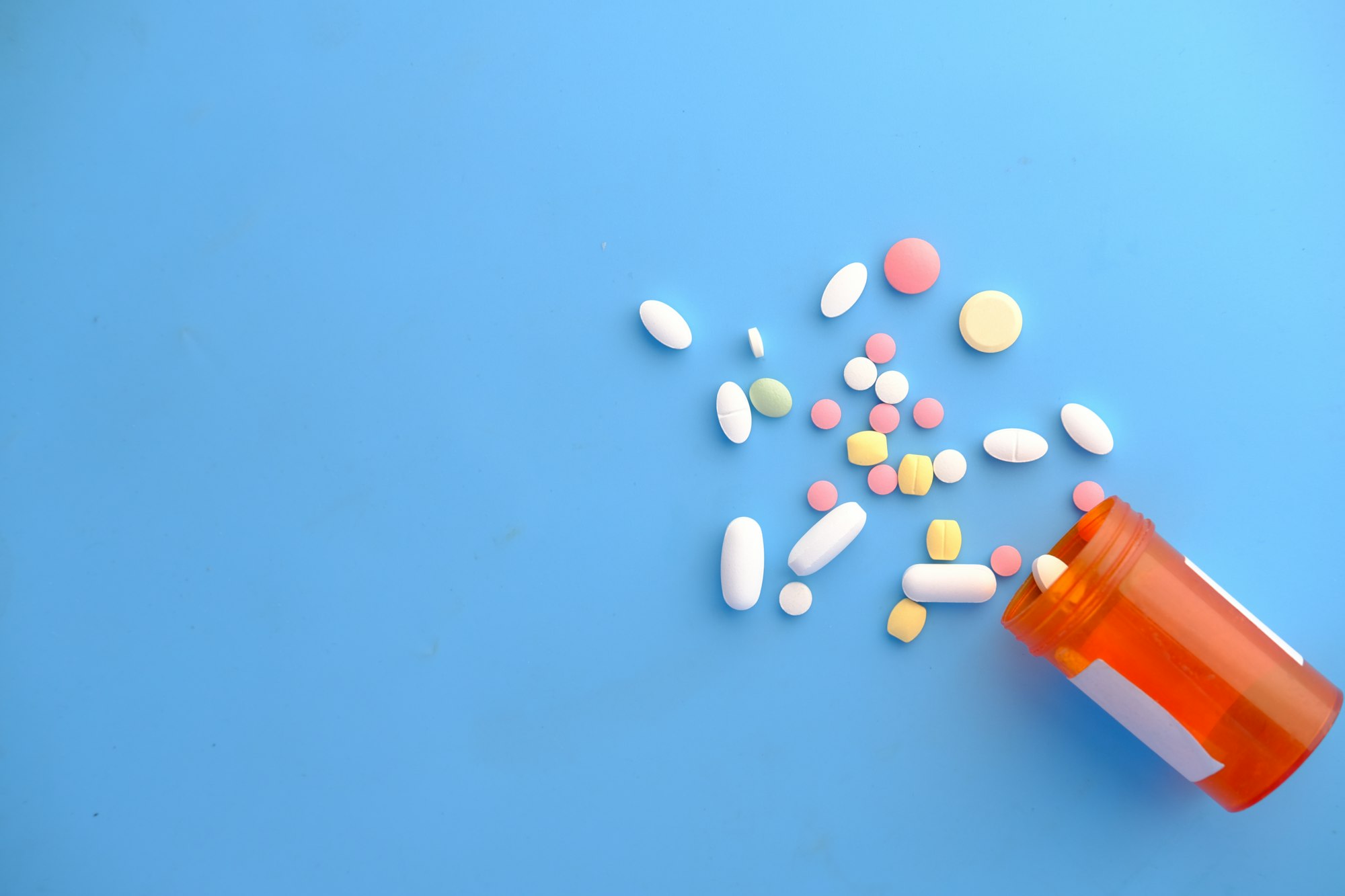 Prescription pills spilling from an amber medication bottle