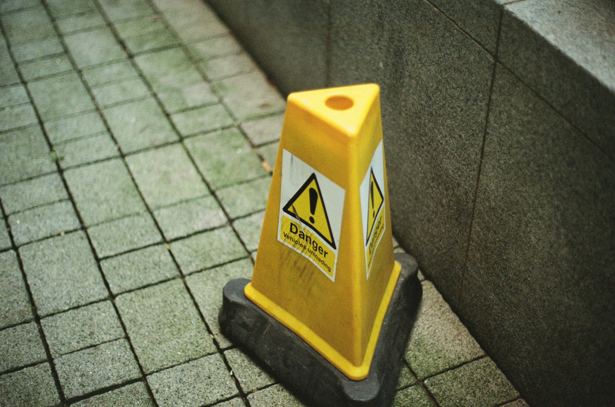 A yellow wet floor caution cone on a tiled surface