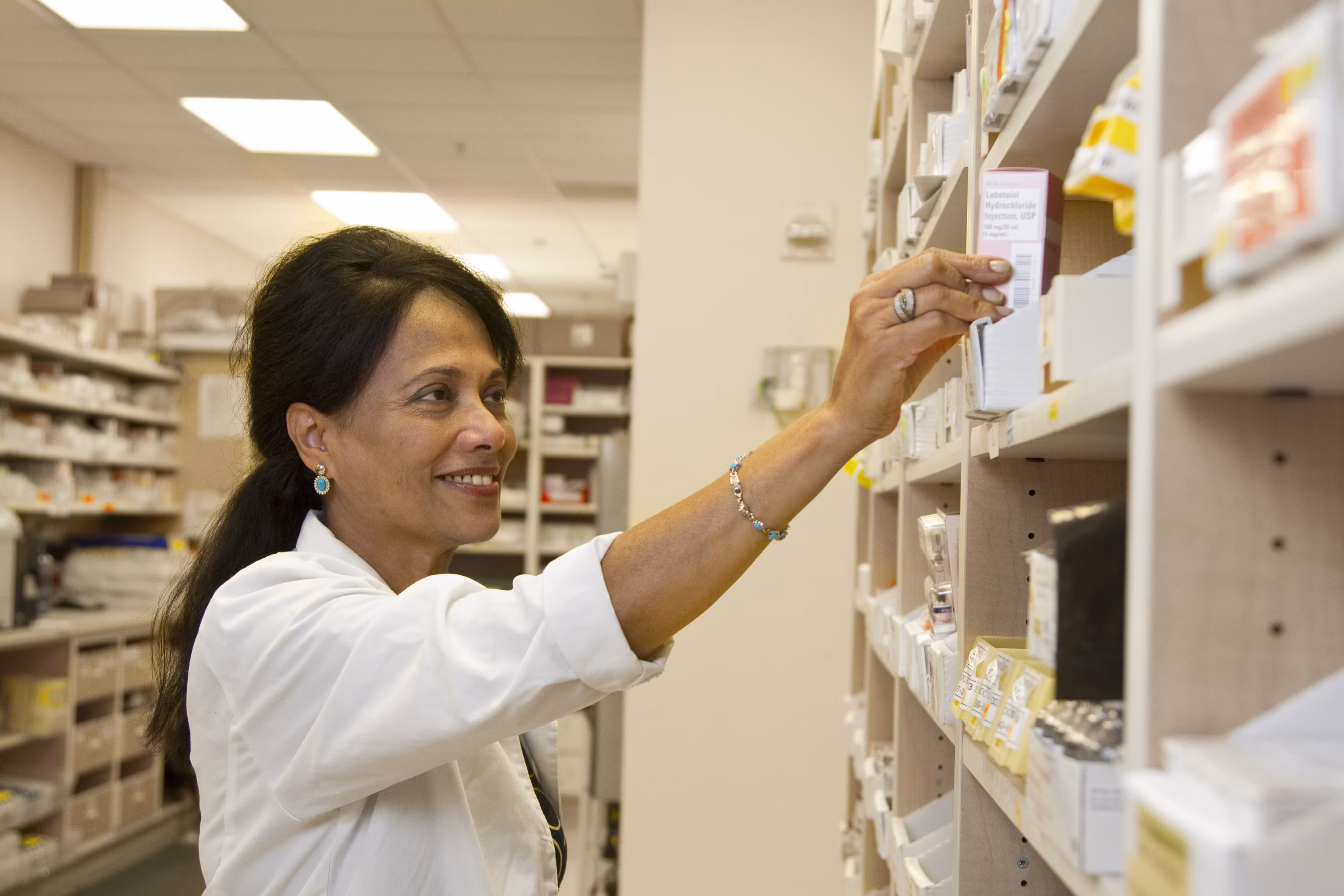 Pharmacist reviewing medication on a pharmacy shelf