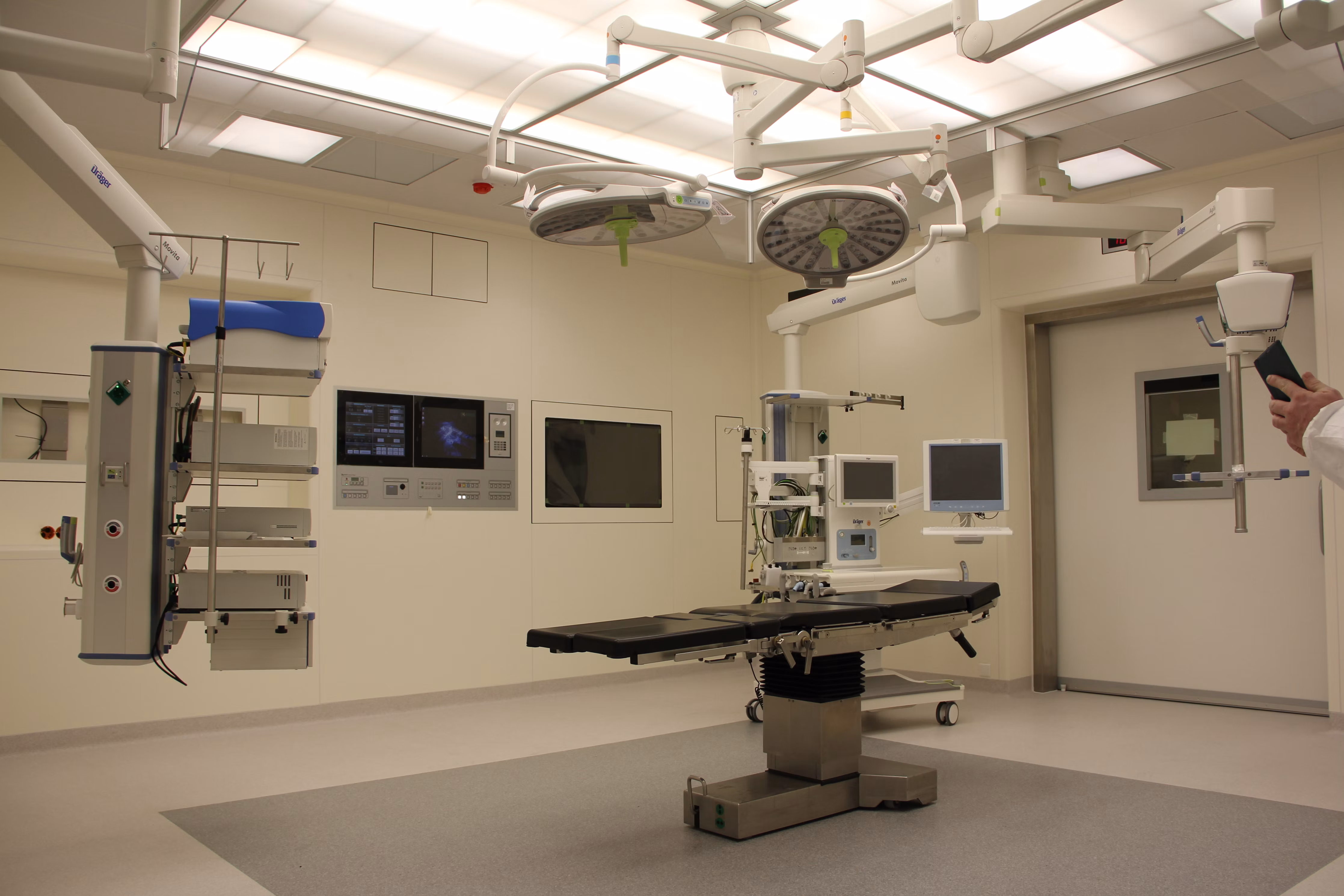 Empty operating room with a surgical table, overhead lights and monitoring equipment