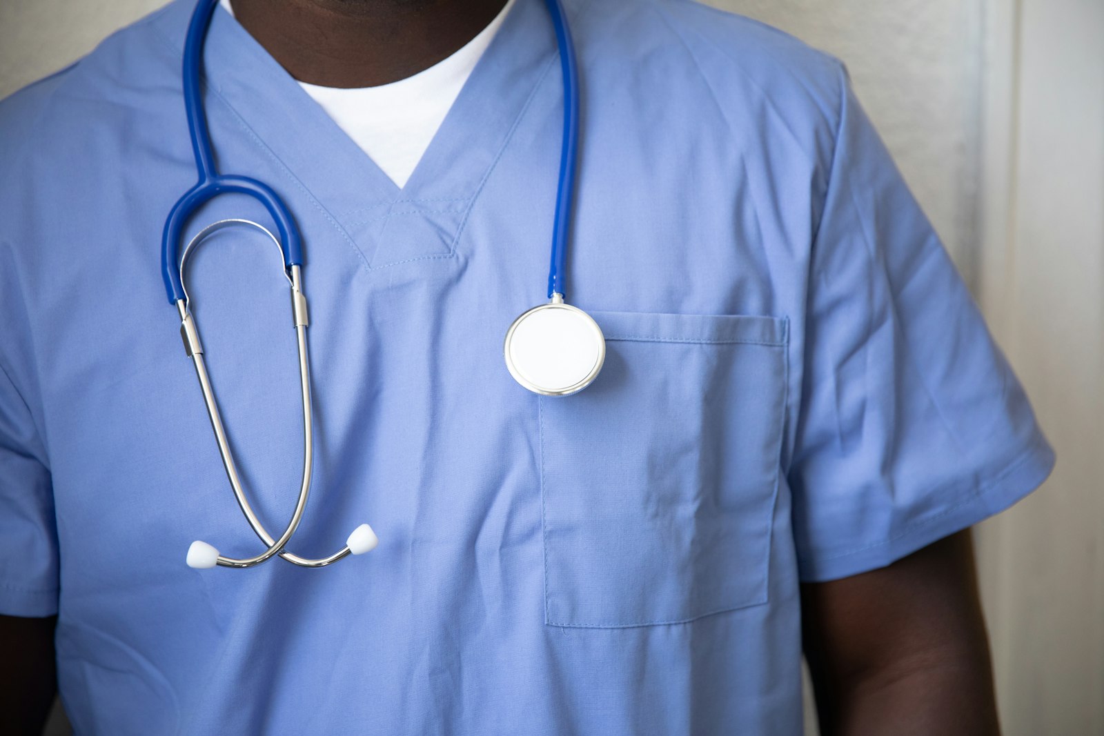 A healthcare worker in blue scrubs with a stethoscope