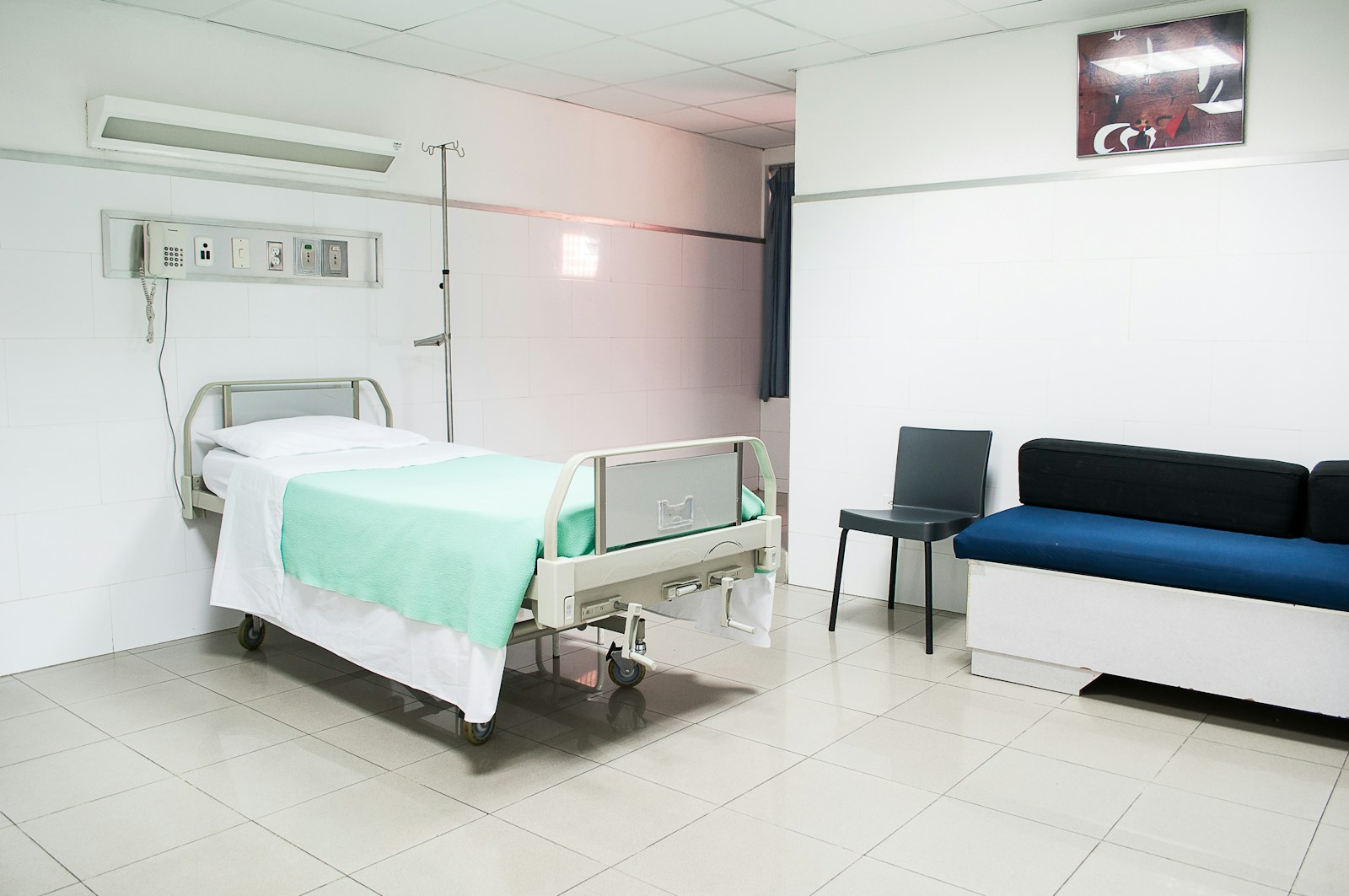 A hospital room with a bed and seating for visitors
