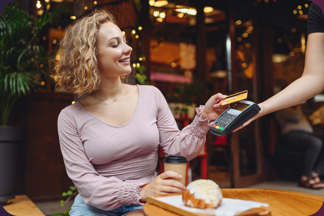 A woman paying with a credit card at a cafe counter