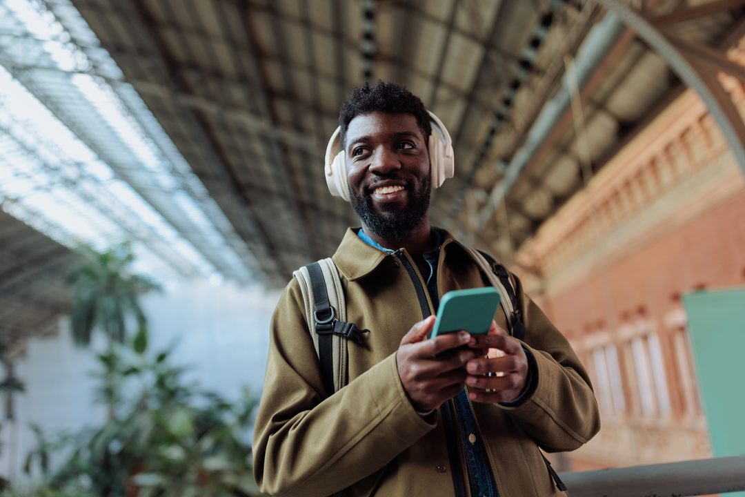 A man checking his phone while waiting in a transit station