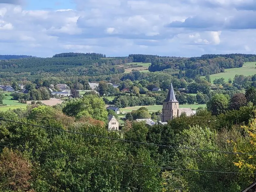 Uitzicht vanuit de familiekamer op Grandmenil met de kerktoren en de beboste heuvels