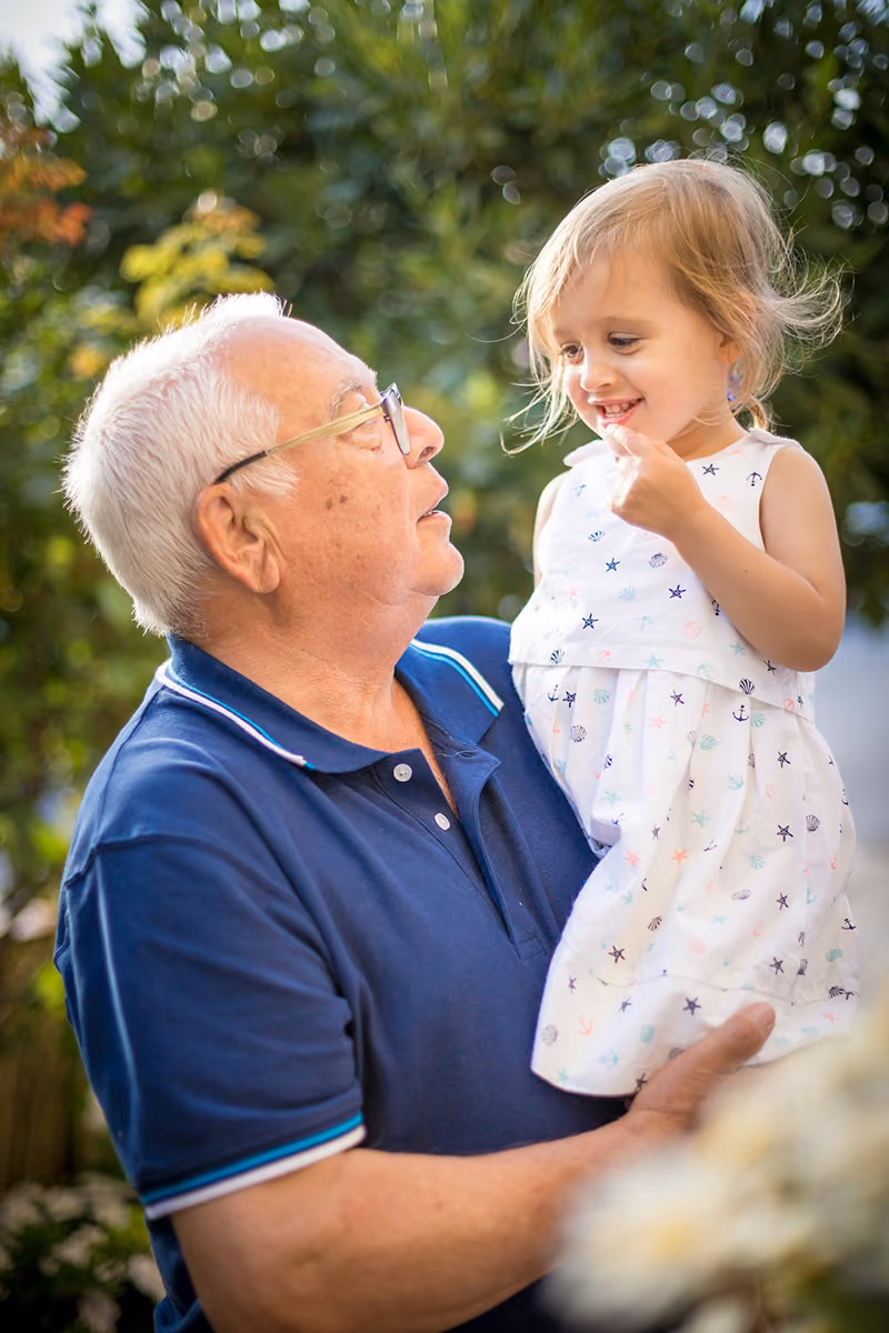 A grandfather holding his granddaughter