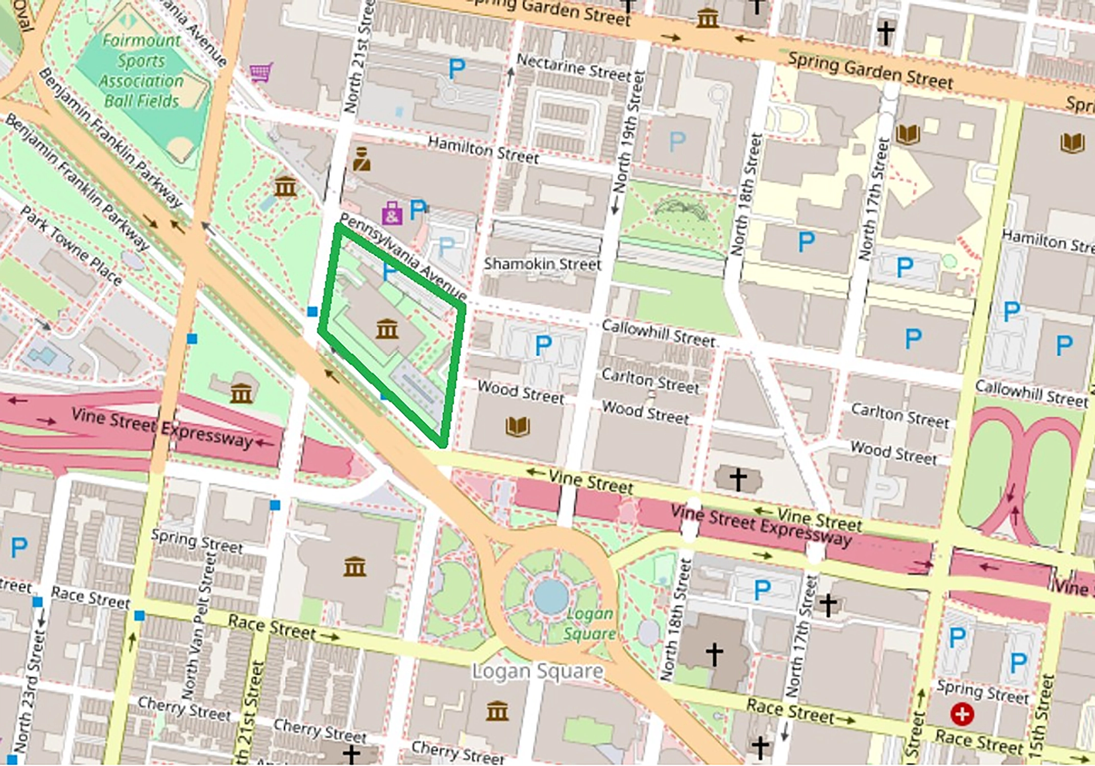 Map of an urban area showing streets including Vine Street Expressway, Pennsylvania Avenue, Race Street, and Spring Garden Street. Logan Square with a roundabout and green land is visible in the center. Several parking locations marked with a P, multiple building icons representing institutions or landmarks, and religious buildings marked with crosses are also featured. The map highlights a green-bordered area along Pennsylvania Avenue near Vine Street Expressway. Nearby parks and the Fairmount Sports Association Ball Fields are in the upper left.