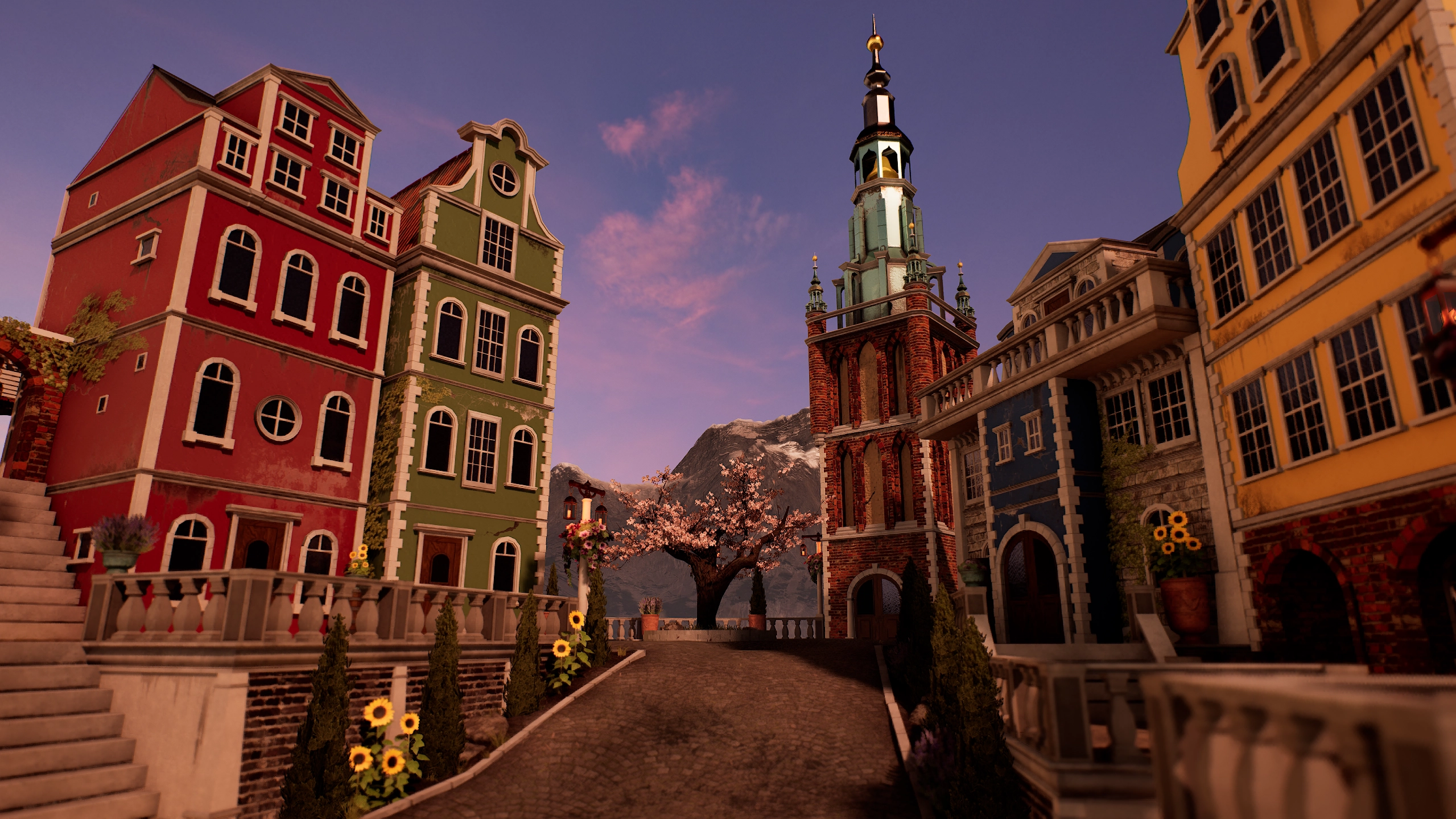 A cobblestone street in a European-style village lined with colorful buildings in red, green, blue, and yellow, featuring a tall brick church tower, potted sunflowers, and a blossoming tree against a backdrop of mountains at sunset.