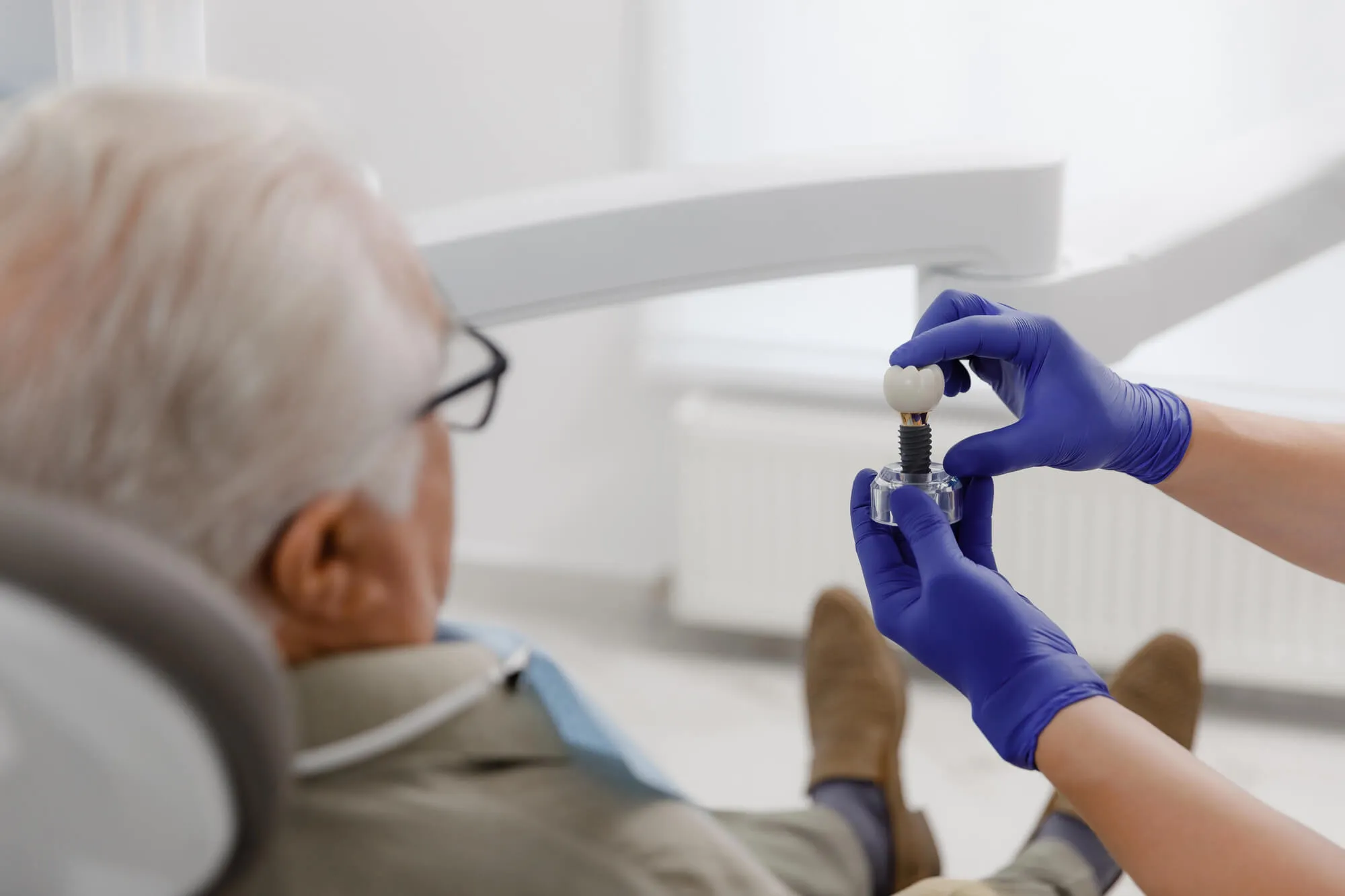 dentist showing model of a dental implant to a male patient