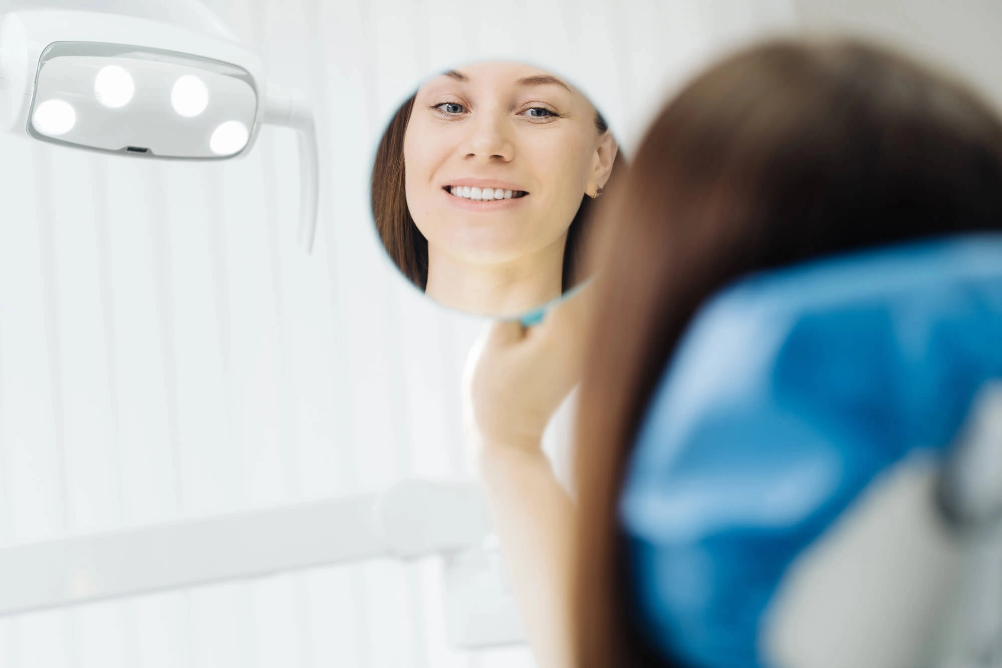 woman looking at her smile in the mirror