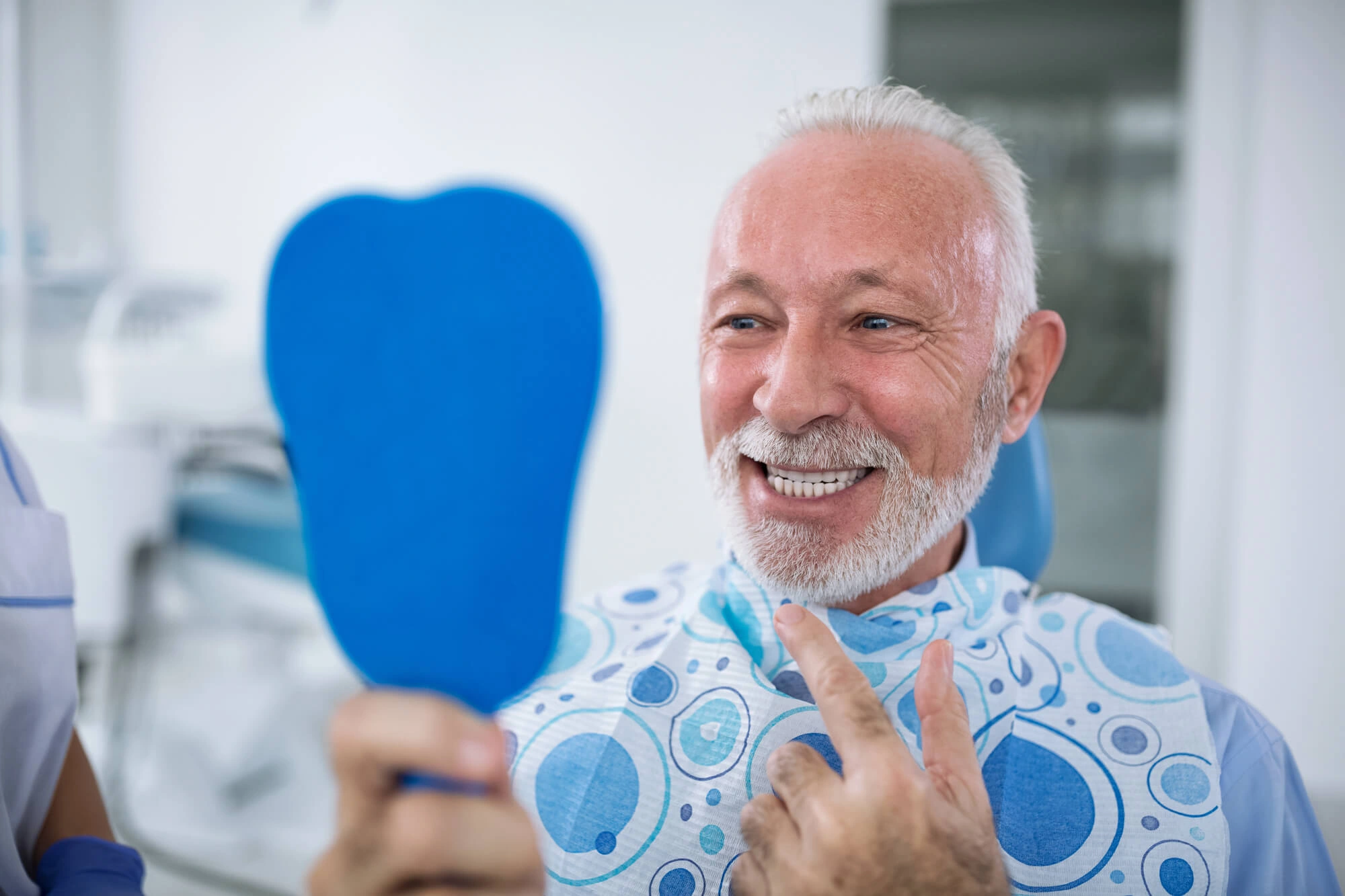 man smiling and looking at his smile in the mirror