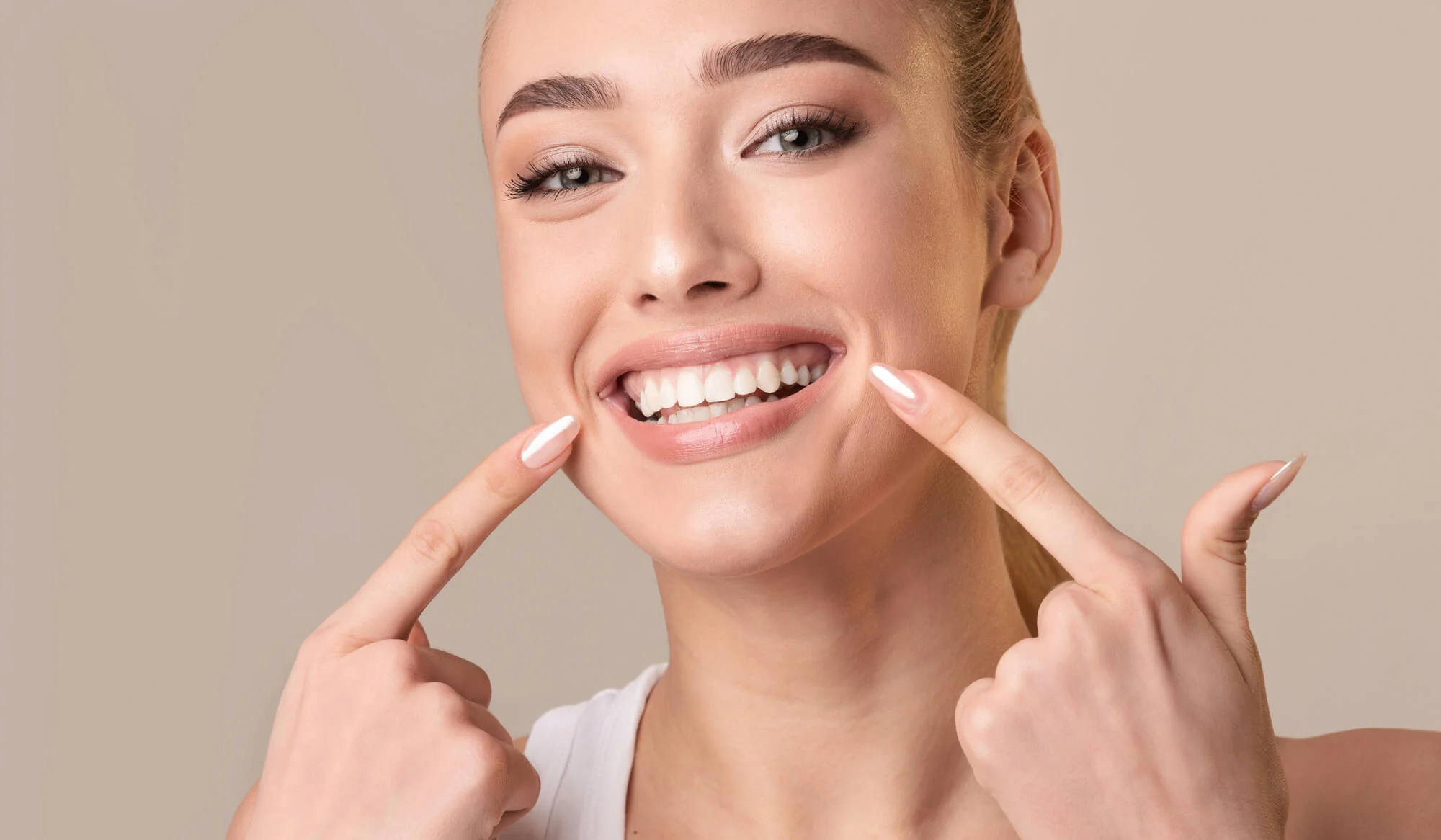 woman smiling and pointing at her smile