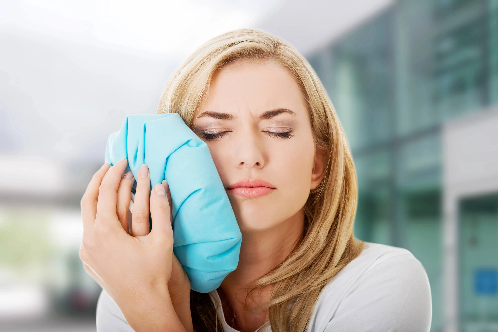 woman in pain putting cold compress in her cheek
