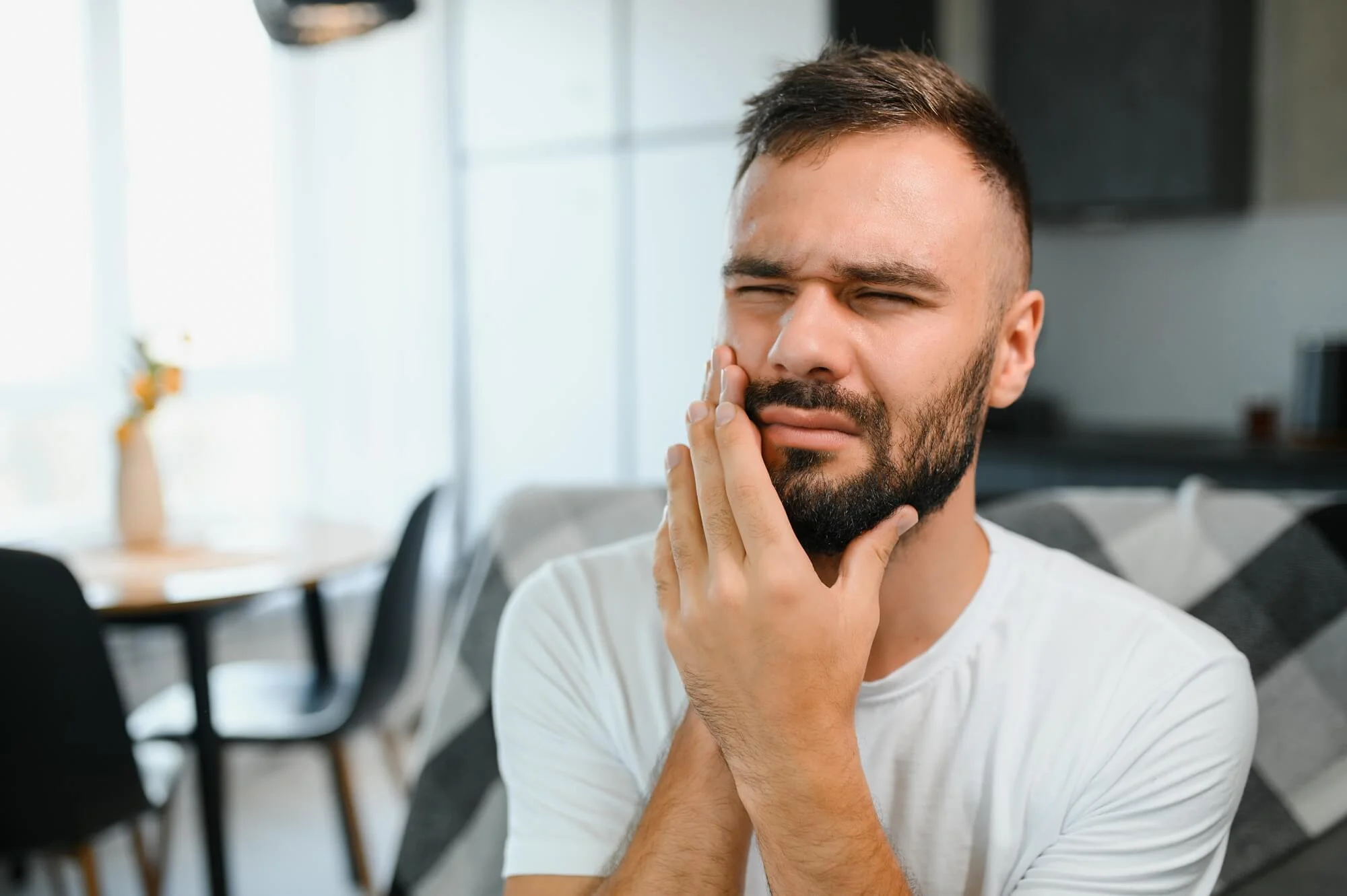 man touching his cheek in dental pain