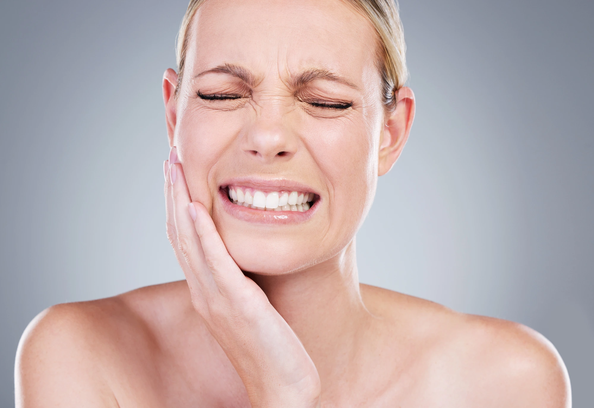 woman touching her cheek due to dental pain