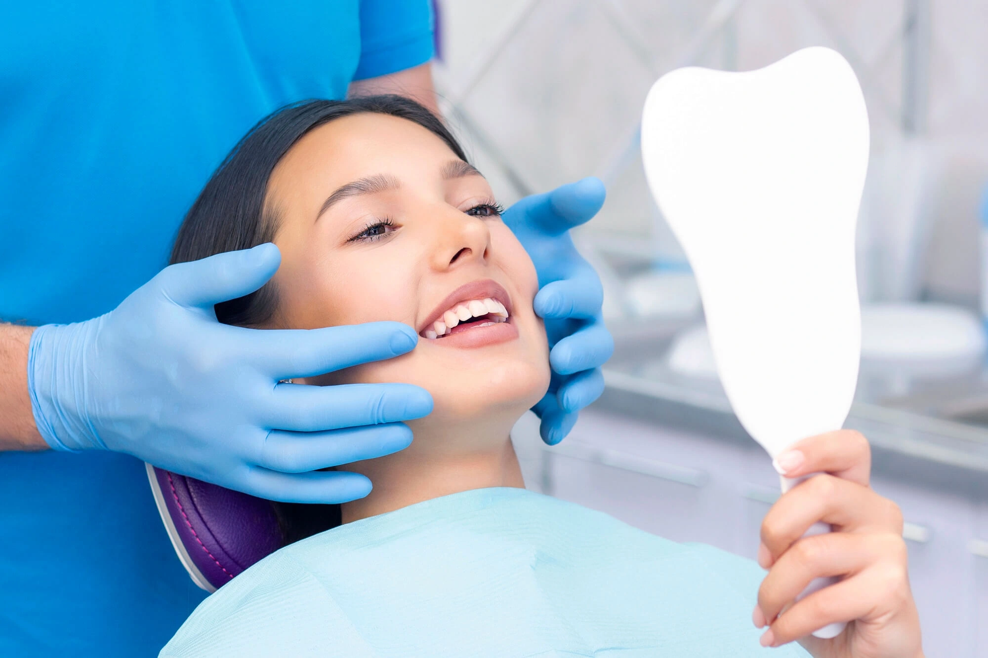 woman smiling at the dentist and looking at her smile in the mirror