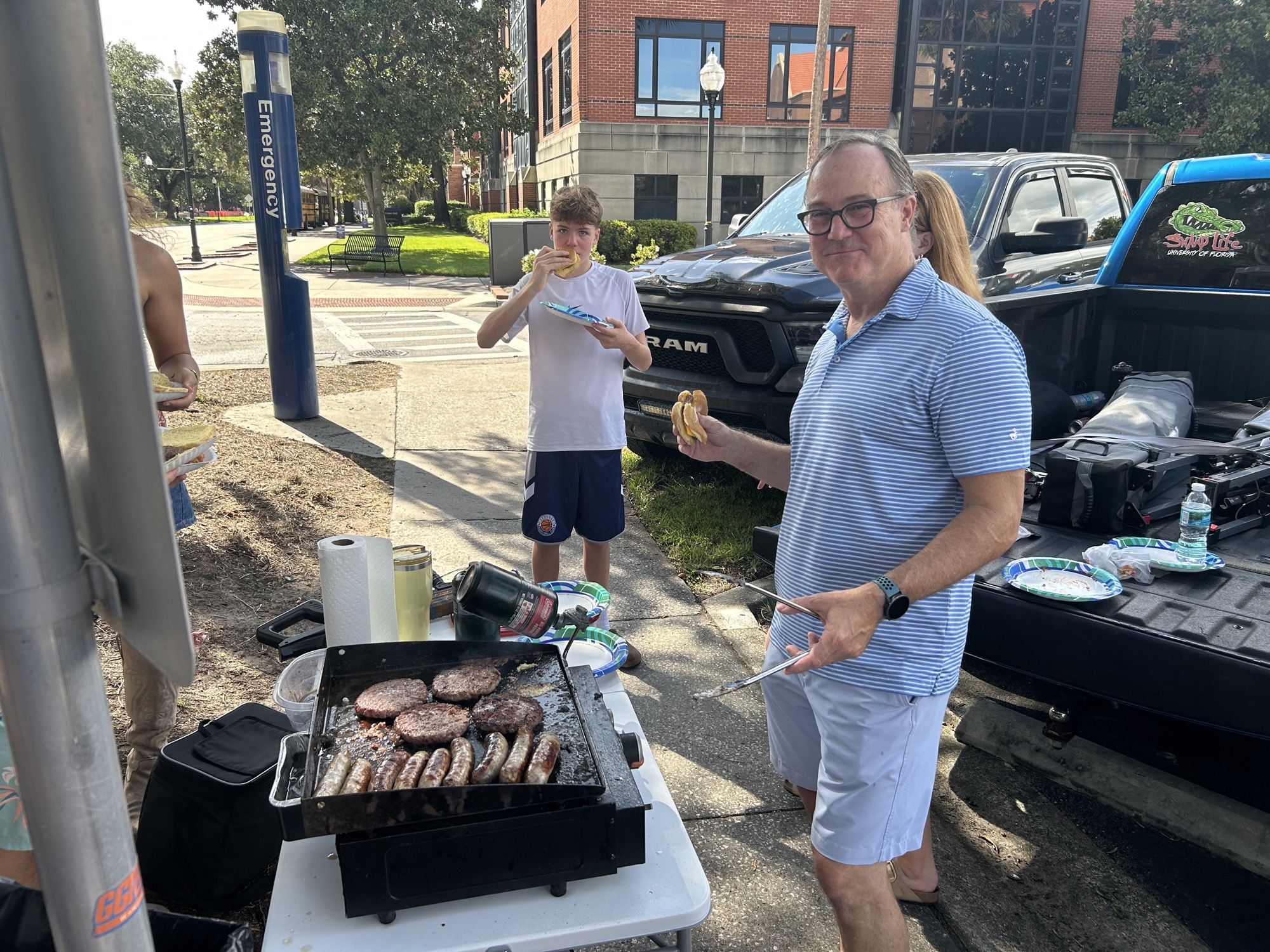 Burgers and bratwurst cooking on a griddle at the tailgate on Union Road