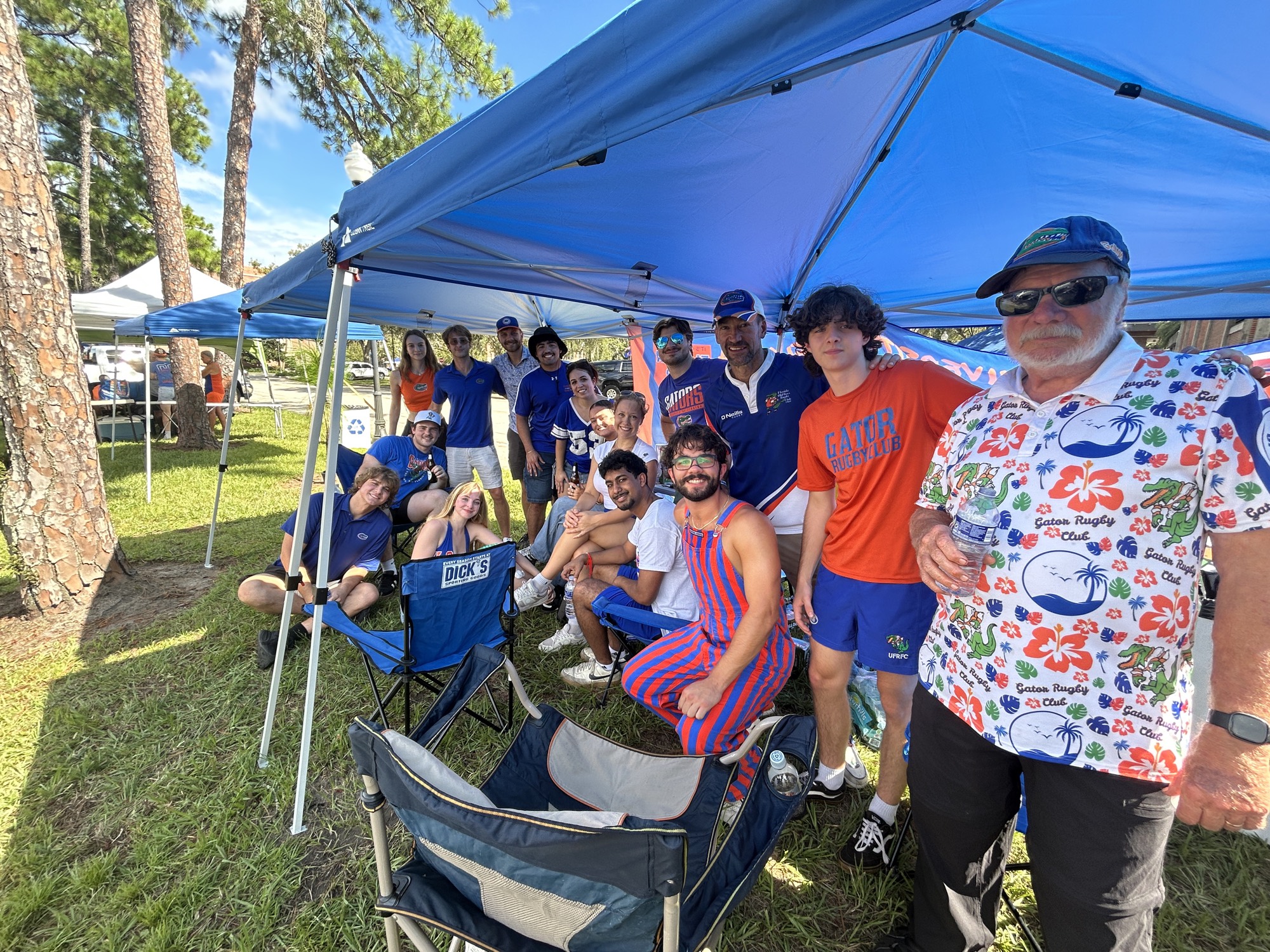 About fifteen Gators rugby players, alumni and family members gathered together under a blue tent at the Union Road tailgate