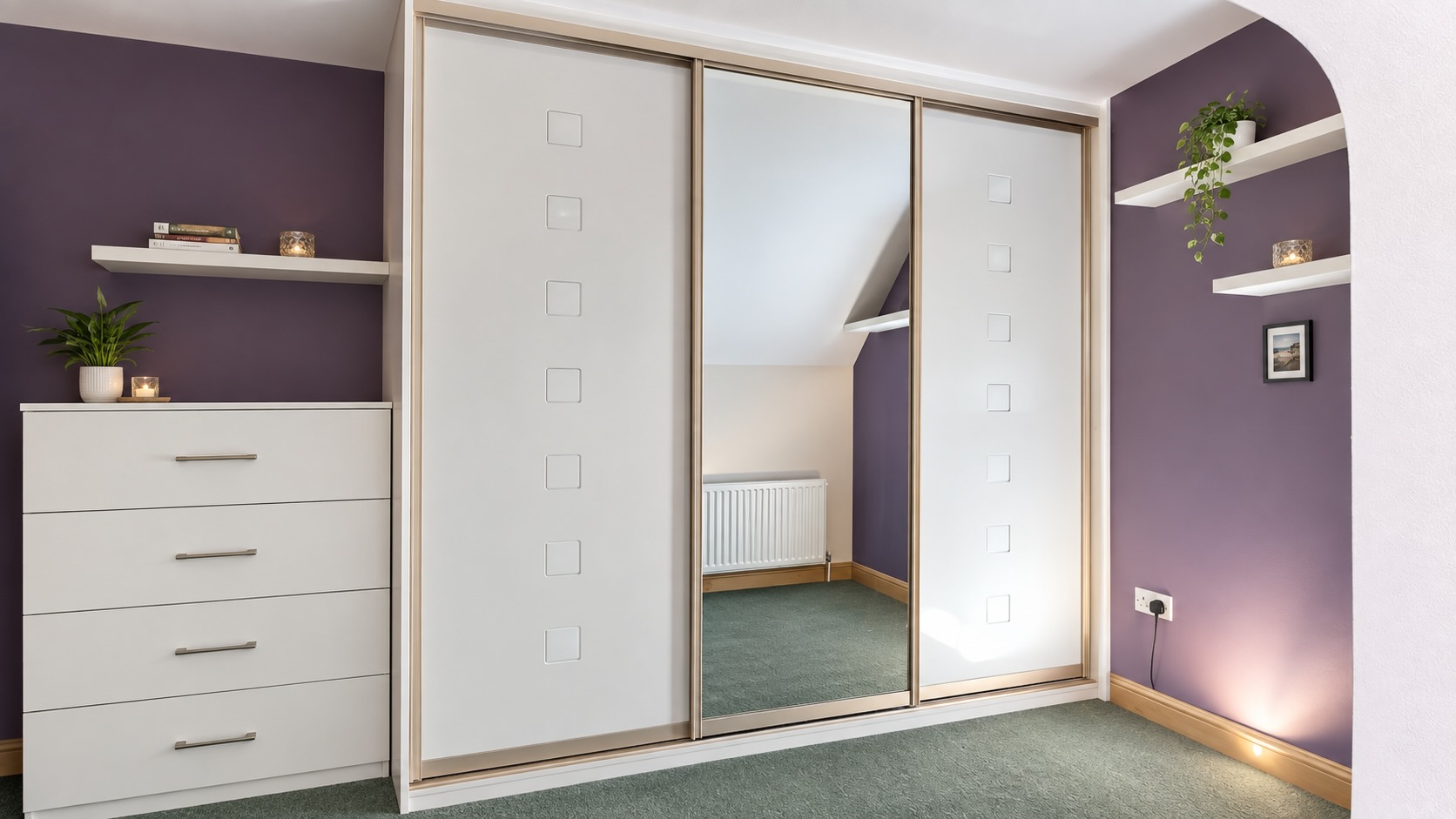 White fitted wardrobe with mirrored sliding doors and a matching chest of drawers. Contemporary bedroom storage with champagne frames, silver handles, and purple wall decor.