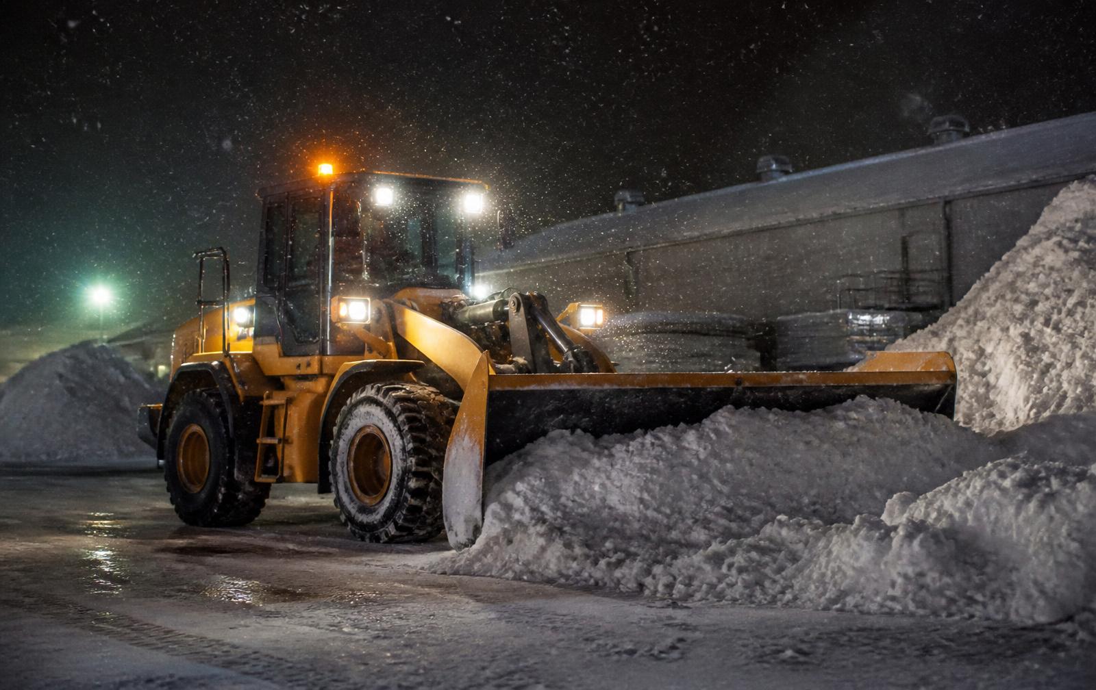 Snow plow clearing a commercial plaza parking lot in Scarborough before opening