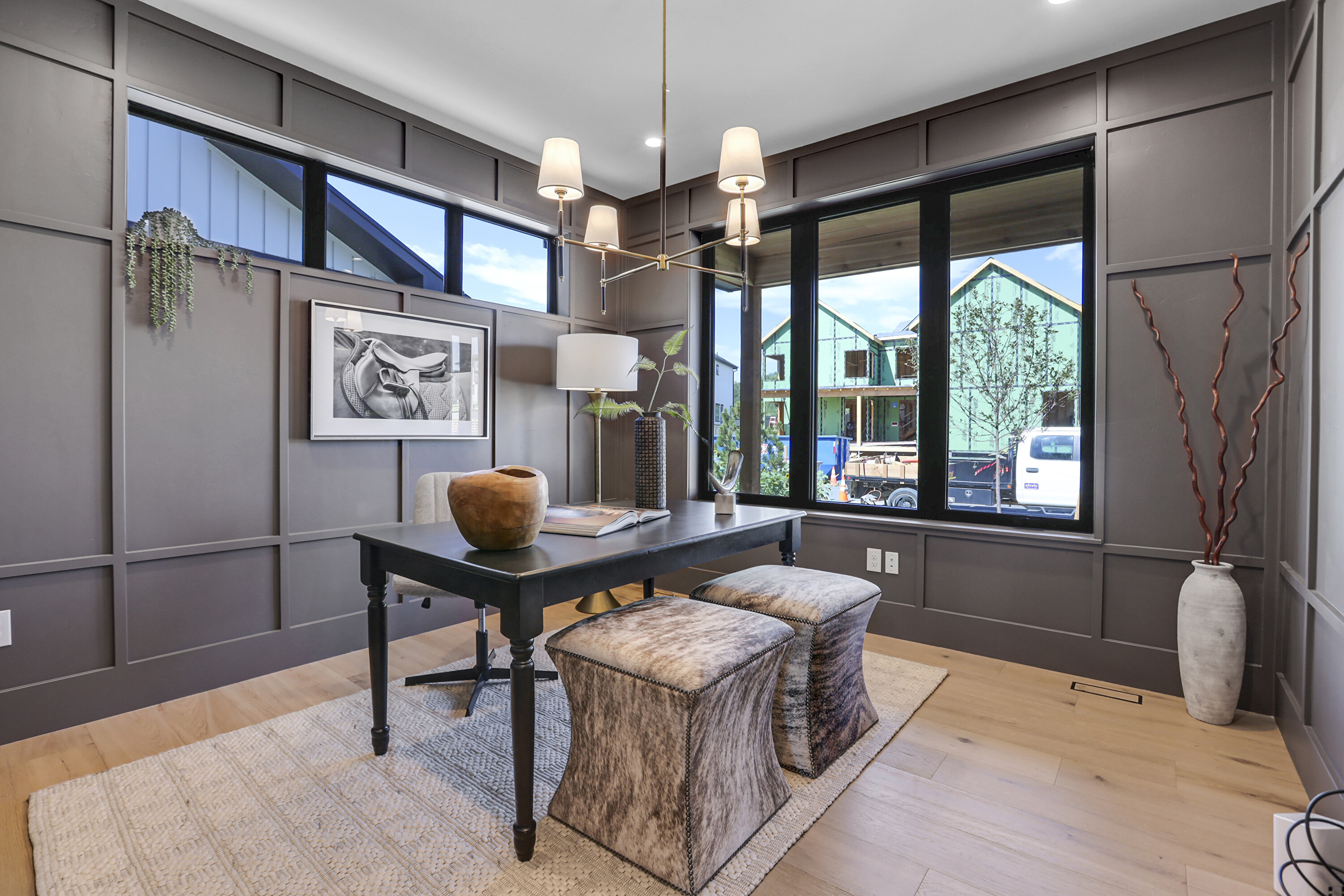 Home office with charcoal paneled walls and large black-frame windows