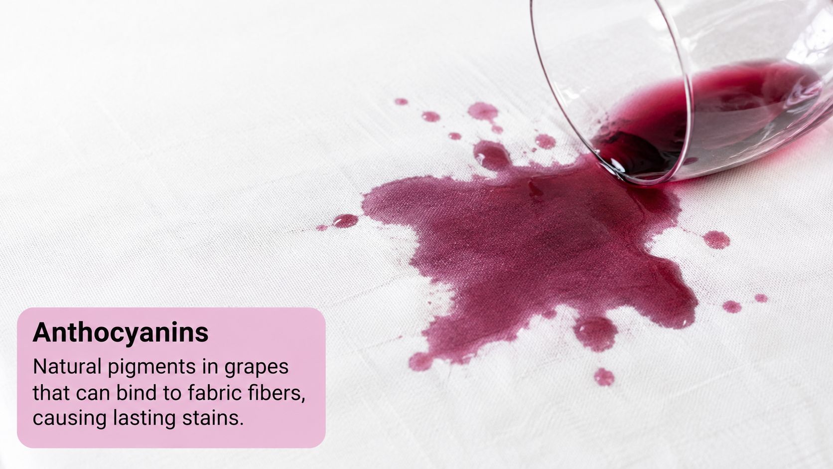 A glass of red wine spilled on a white tablecloth, creating a dark purple stain.