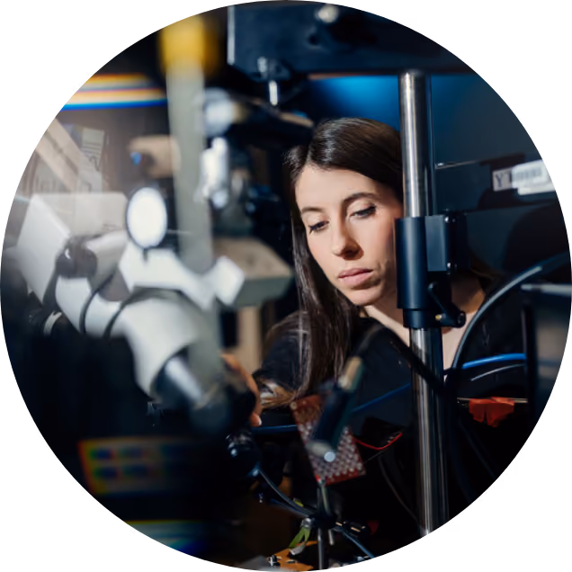 A lab member seated in front of a piece of lab equipment 