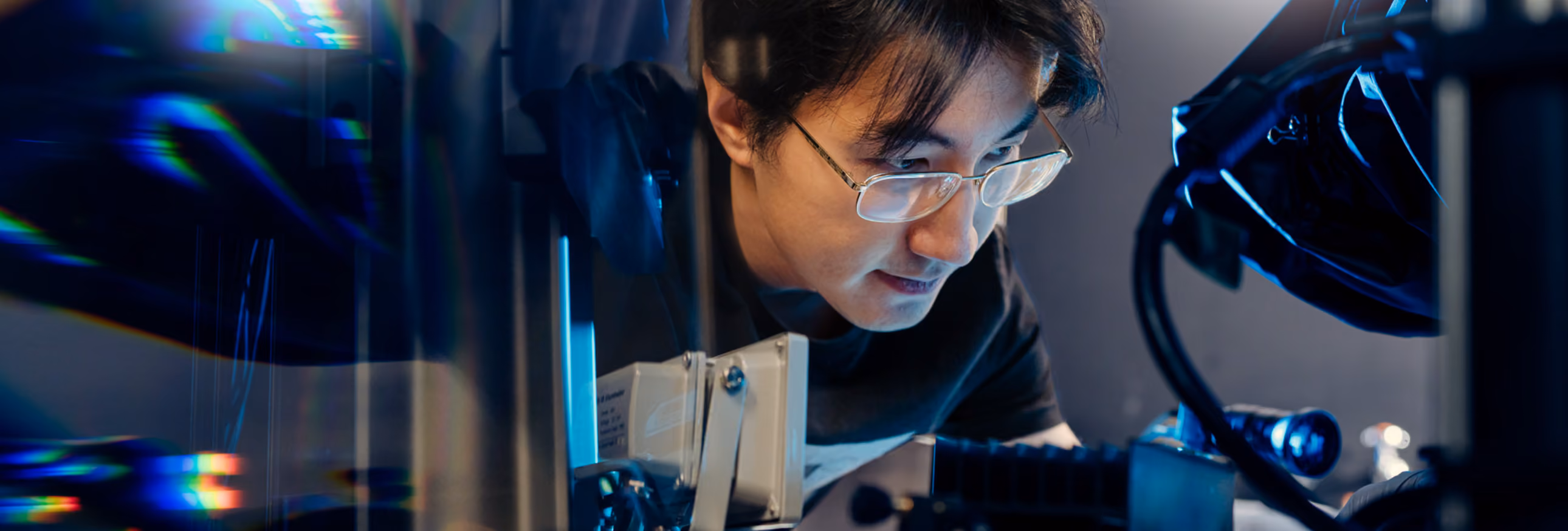 A lab member leaning close to view a piece of lab equipment.