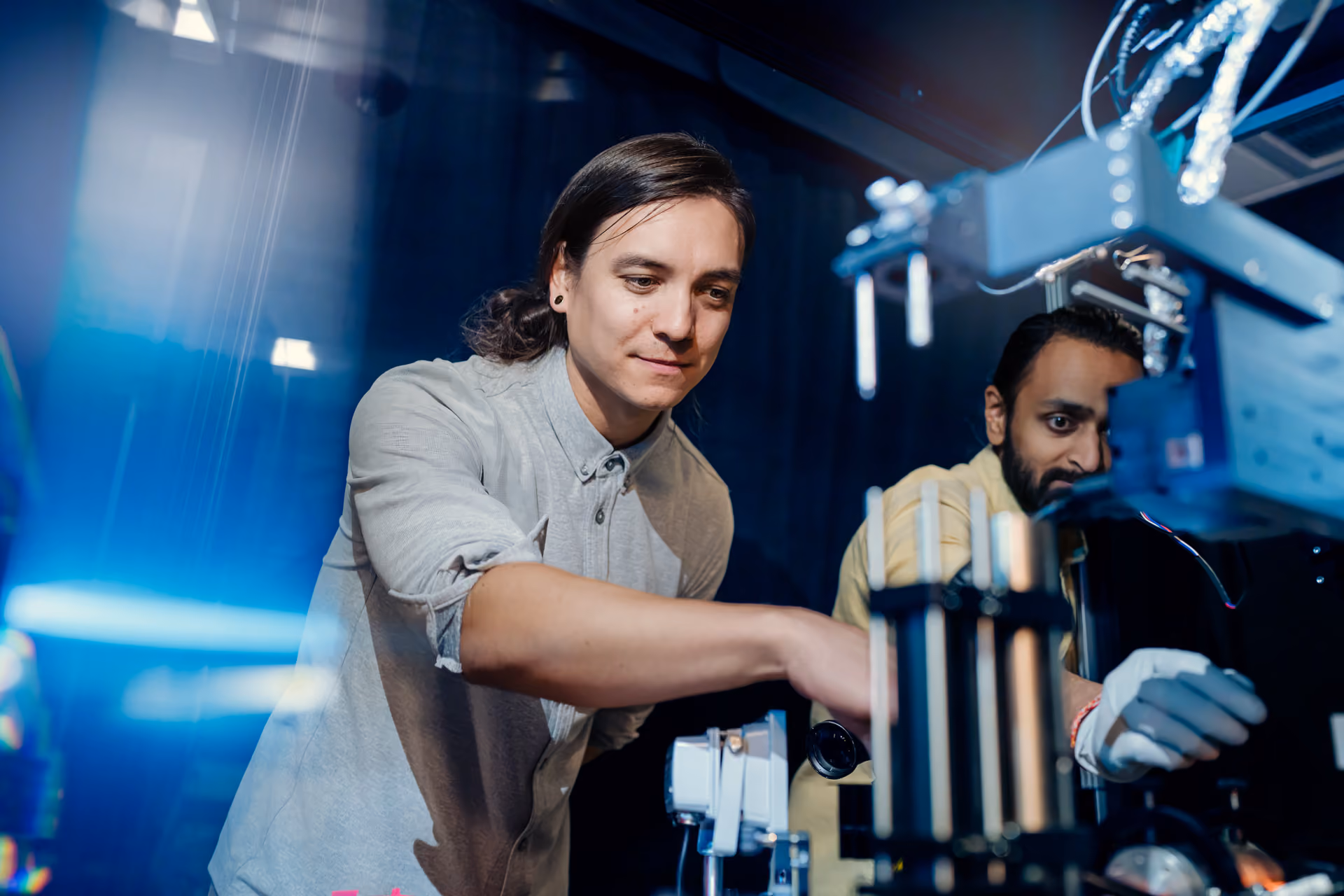 Two lab members adjusting a piece of equipment.