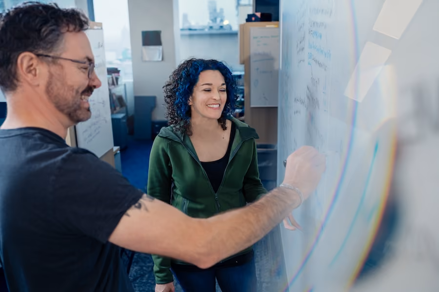 Jess and a lab member drawing on a whiteboard.