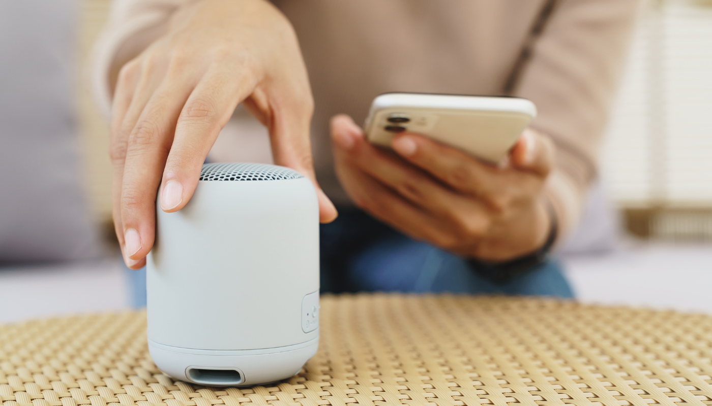 a woman using her mobile phone and a Bluetooth enabled speaker