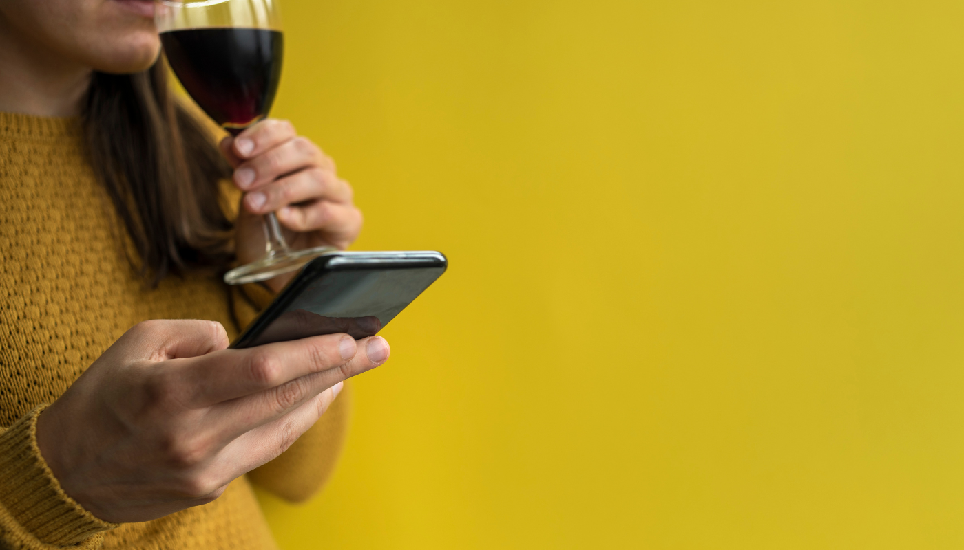 Woman drinking wine looking at phone