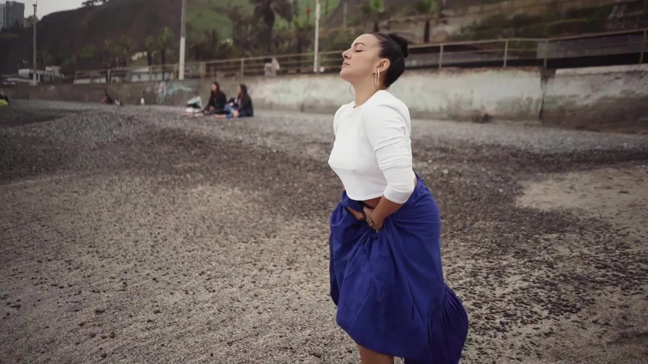 Cynthia Paniagua dancing in a blue skirt on an open shoreline in Peru