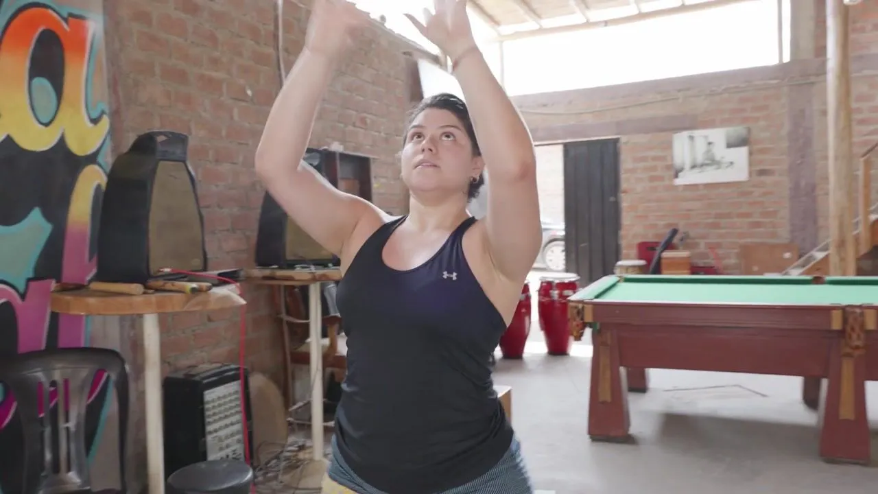 A dancer mid-movement with arms raised during a Dance Your Ancestors session