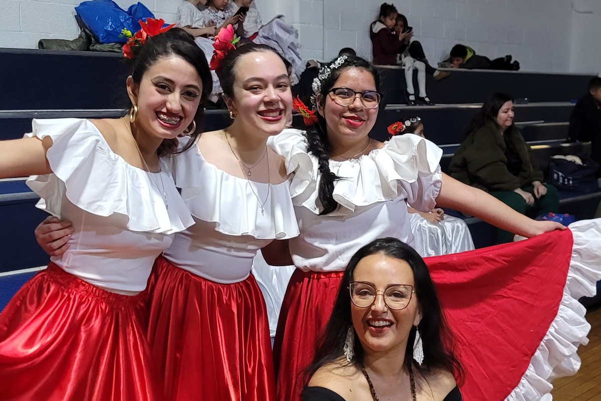 Cynthia Paniagua with three students in red and white folkloric skirts
