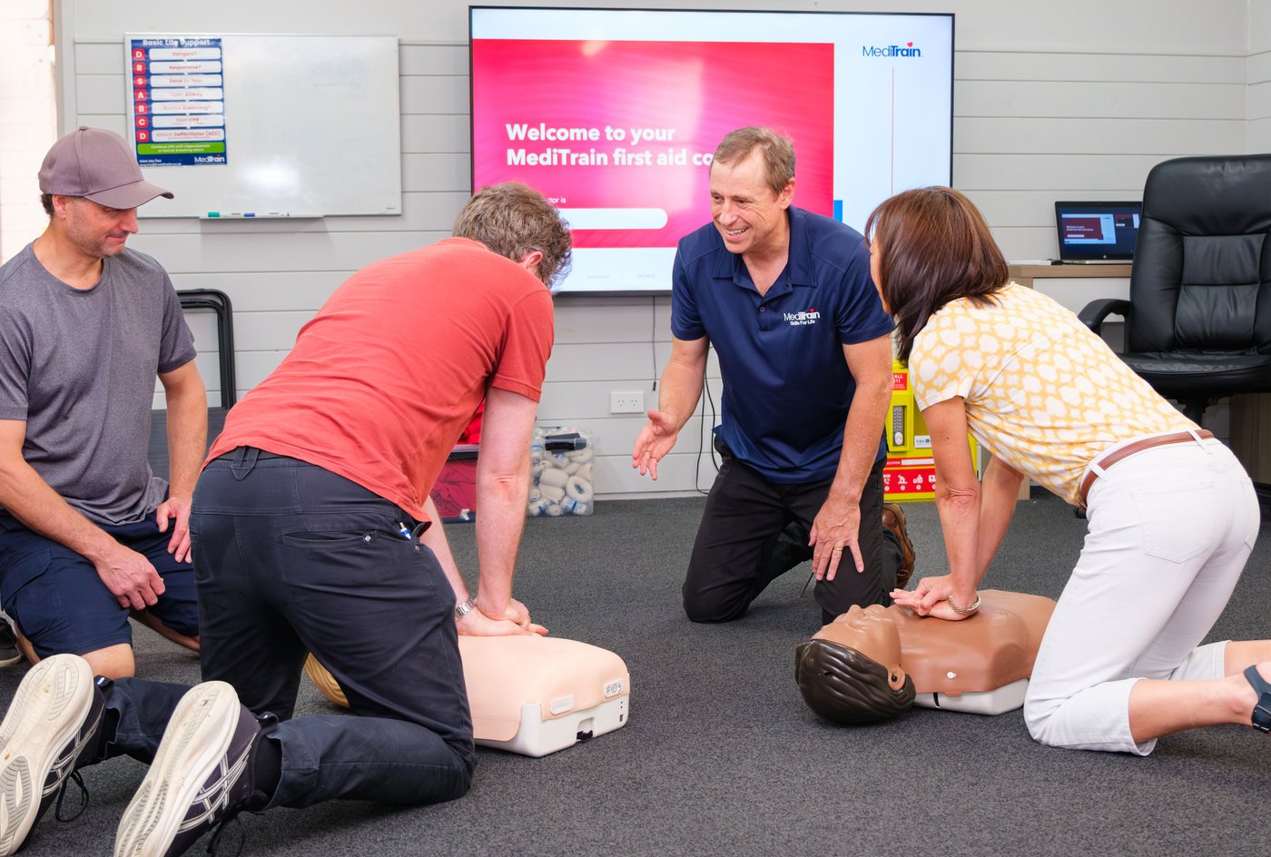MediTrain instructor coaching two learners through chest compressions on CPR manikins