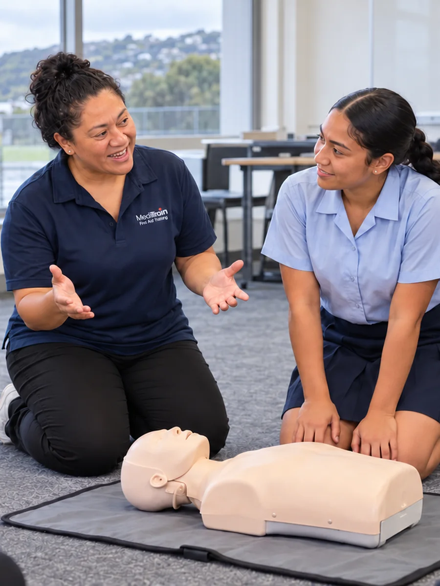 Secondary school students learning CPR on a manikin with a MediTrain instructor
