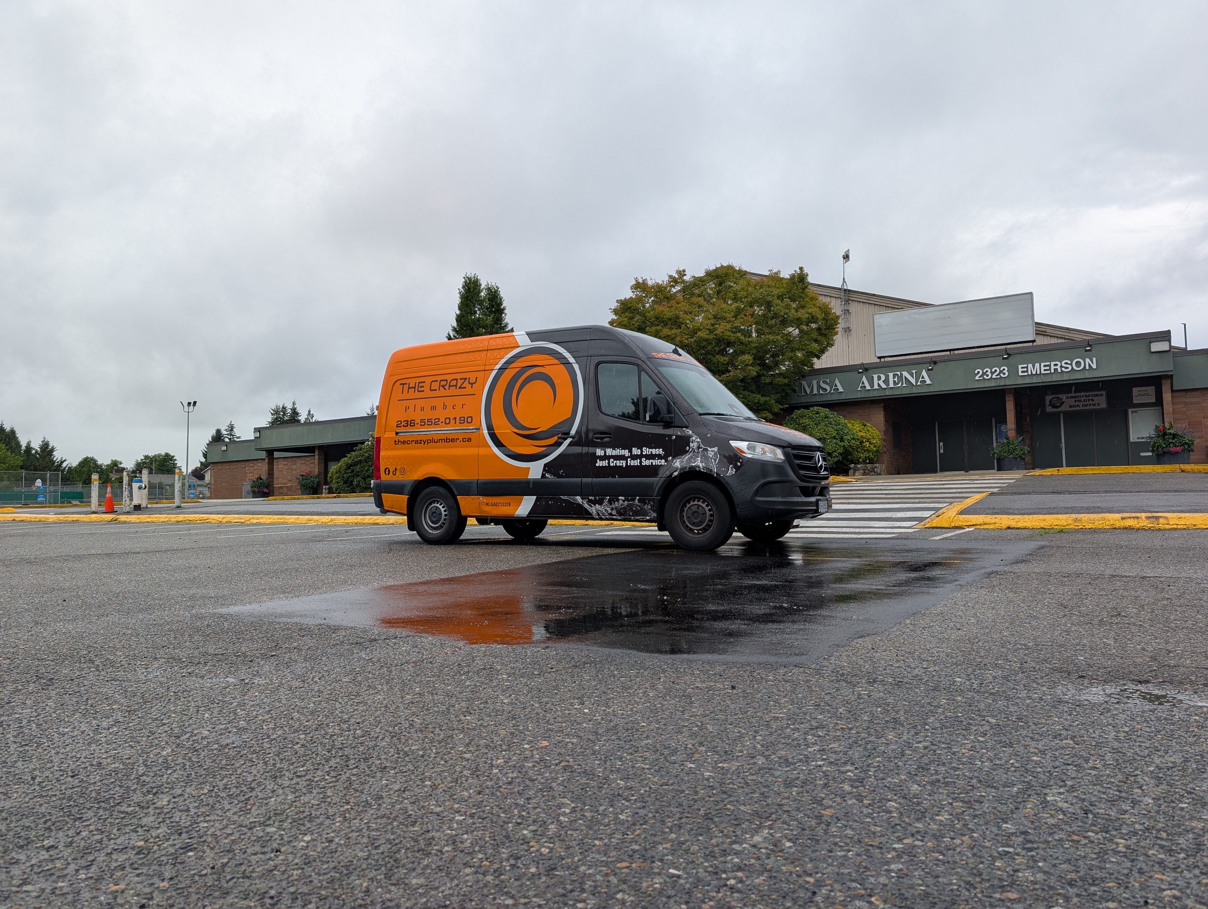 The Crazy Plumber's service van parked outside MSA Arena on Emerson Street in Abbotsford on an overcast day.